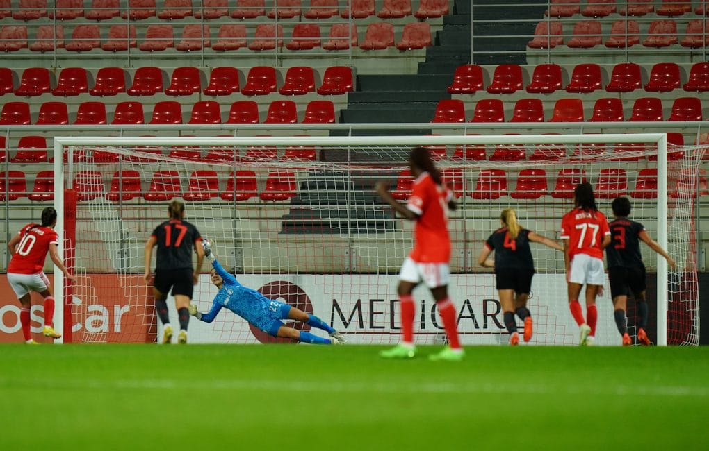 Mala Grohs pariert einen Elfmeter. Um sie herum sind mehrere Spielerinnen zu sehen, im Hintergrund eine leere Tribüne.